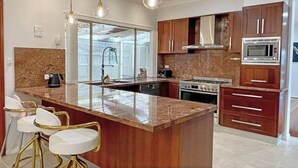 Una cocina moderna con una isla central, electrodomésticos de acero inoxidable y armarios de madera.