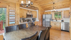 A wooden cabin-style kitchen with a dining table, chairs, and modern appliances.