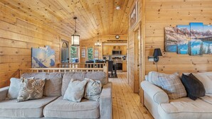 A cozy cabin interior with wooden walls, a dining area, and a kitchen.