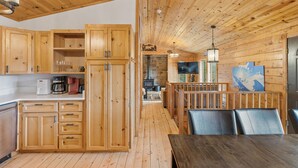 A wooden interior with a kitchen, dining area, and a fireplace.