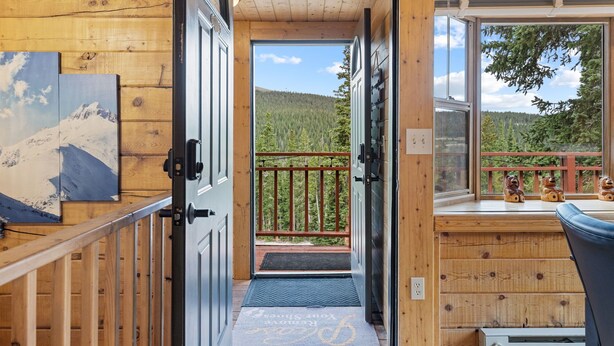 A wooden cabin interior with a view of a forested mountain.
