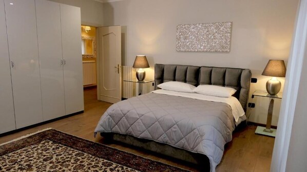 Un dormitorio con cama, lámparas de noche, un armario y un elemento decorativo en la pared.
