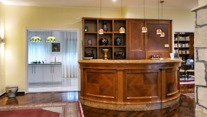 Una zona con barra de madera con estante empotrado, una cocina al fondo y una pared de piedra.
