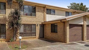 A two-story brick building with a garage and a covered entryway. - Our Townhouse in Toowoomba (Newtown)
