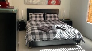 A bedroom with a bed, a ceiling fan, a wall art piece, and a window with blinds. - Our Townhouse in Toowoomba (Newtown)