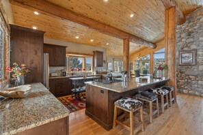 A spacious kitchen with wooden beams, granite countertops, and a large island with bar stools. - River Frontage, Air Conditioning, Private Hot Tub, Ping Pong, 12 minutes to downtown Durango (Durango)