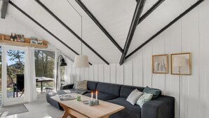 Una sala de estar moderna con un sofá gris oscuro, una mesa de centro de madera y un techo con vigas a la vista.