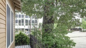 A wooden building with a metal railing and a tree in front. - The Carriage House Downtown Lafayette, LA (Lafayette)