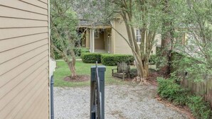 A residential property with a gravel driveway, a wooden deck, and a small garden area with a potted plant. - The Carriage House Downtown Lafayette, LA (Lafayette)
