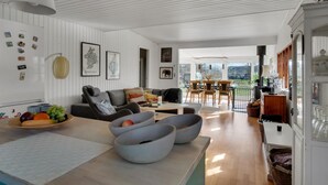 A modern living room with a sofa, coffee table, and bowls of fruit. There are framed pictures on the wall and a view of the outdoors. - Beautiful home in Grevinge with kitchen (Grevinge)