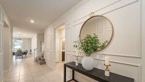 A hallway with a dark console table, a round mirror, a potted plant, and a candle.