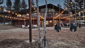 Een rustieke lodge met een overdekt terras, buiten zitplaatsen en sfeerverlichting.