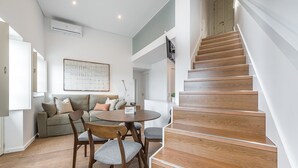 Un salon moderne avec un escalier en bois, une table à manger ronde et un canapé.
