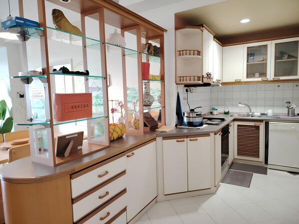 A modern kitchen with white cabinets, a glass display case, and a built-in stove. - Natol Homestay-Riverbank Suites High Rise City Centre (Kuching)