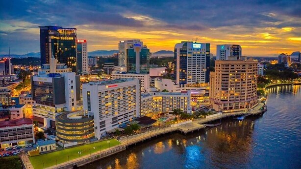 A cityscape with modern buildings, a waterfront, and a bridge. - Natol Homestay-Riverbank Suites High Rise City Centre (Kuching)