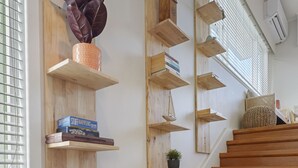 A wooden staircase with built-in shelves holding books, a vase, and a potted plant. - Amazing Home By Beach - Aircon-ed  (Auckland)