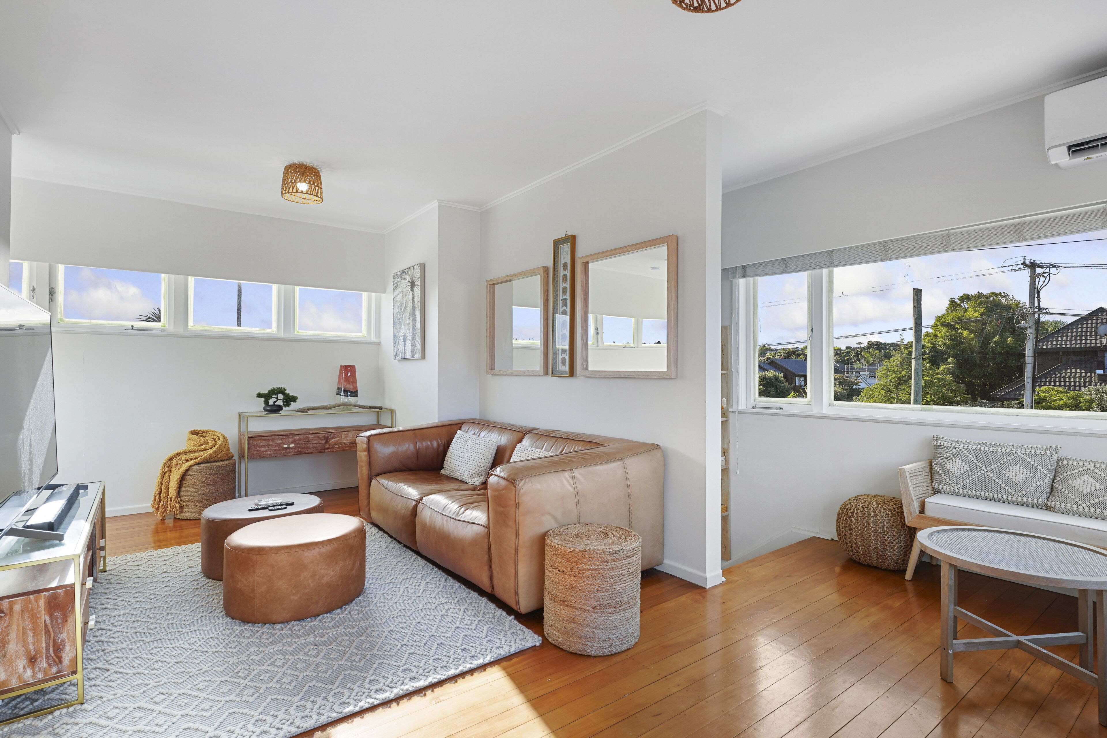 A modern living room with a leather sofa, round ottoman, and a small table.
