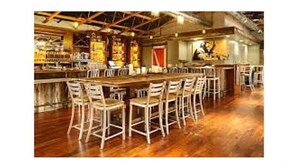 Uma área de bar com banquetas de madeira e um balcão comprido.