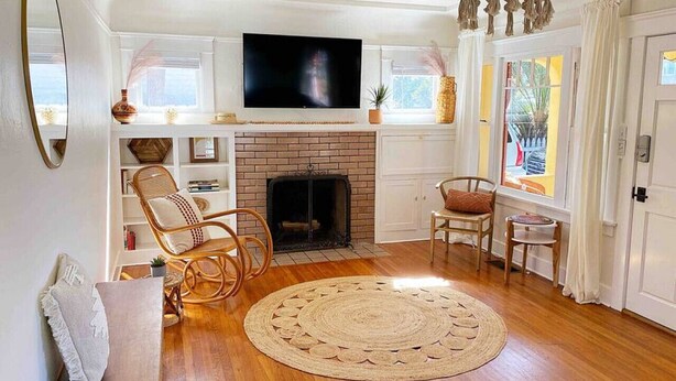 A living room with a fireplace, wooden flooring, a television, and a chandelier.