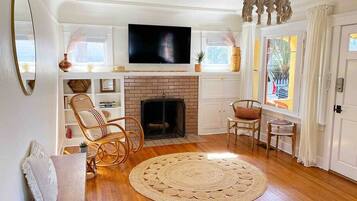 A living room with a fireplace, wooden flooring, a television, and a chandelier.
