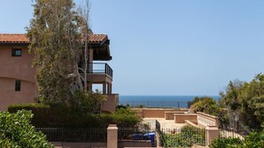 Un edificio de dos pisos con un balcón con vista al mar.