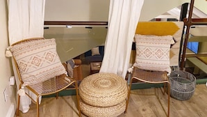 A room with two wicker chairs, a woven ottoman, and a small table. - Indah Jungalow Moonlight, Downtown Encinitas CA (Encinitas)