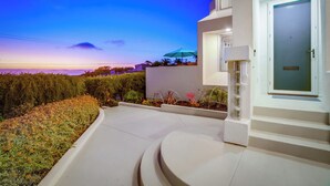 A modern building with a curved driveway, a well-maintained garden, and a door with a glass panel.