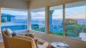 A room with large windows offering a view of a cityscape and greenery.