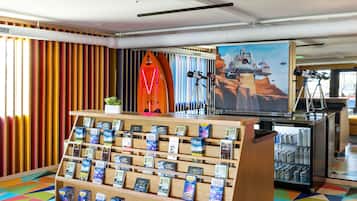 A travel information desk with a display of maps and brochures, a surfboard, and a telescope.