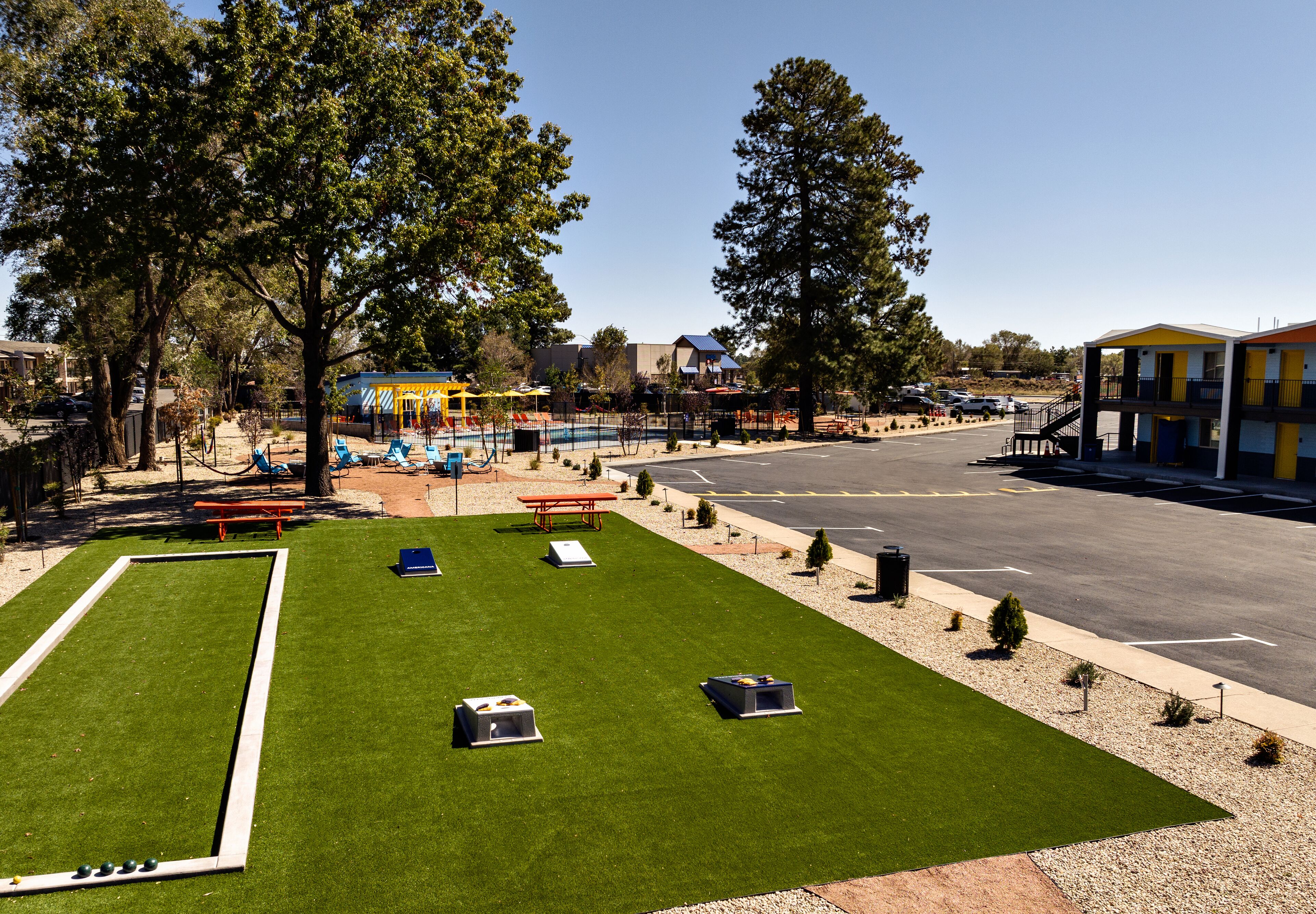 A well-maintained outdoor area with a green lawn, a bocce court, and a parking lot.