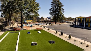 A well-maintained outdoor area with a green lawn, a bocce court, and a parking lot.