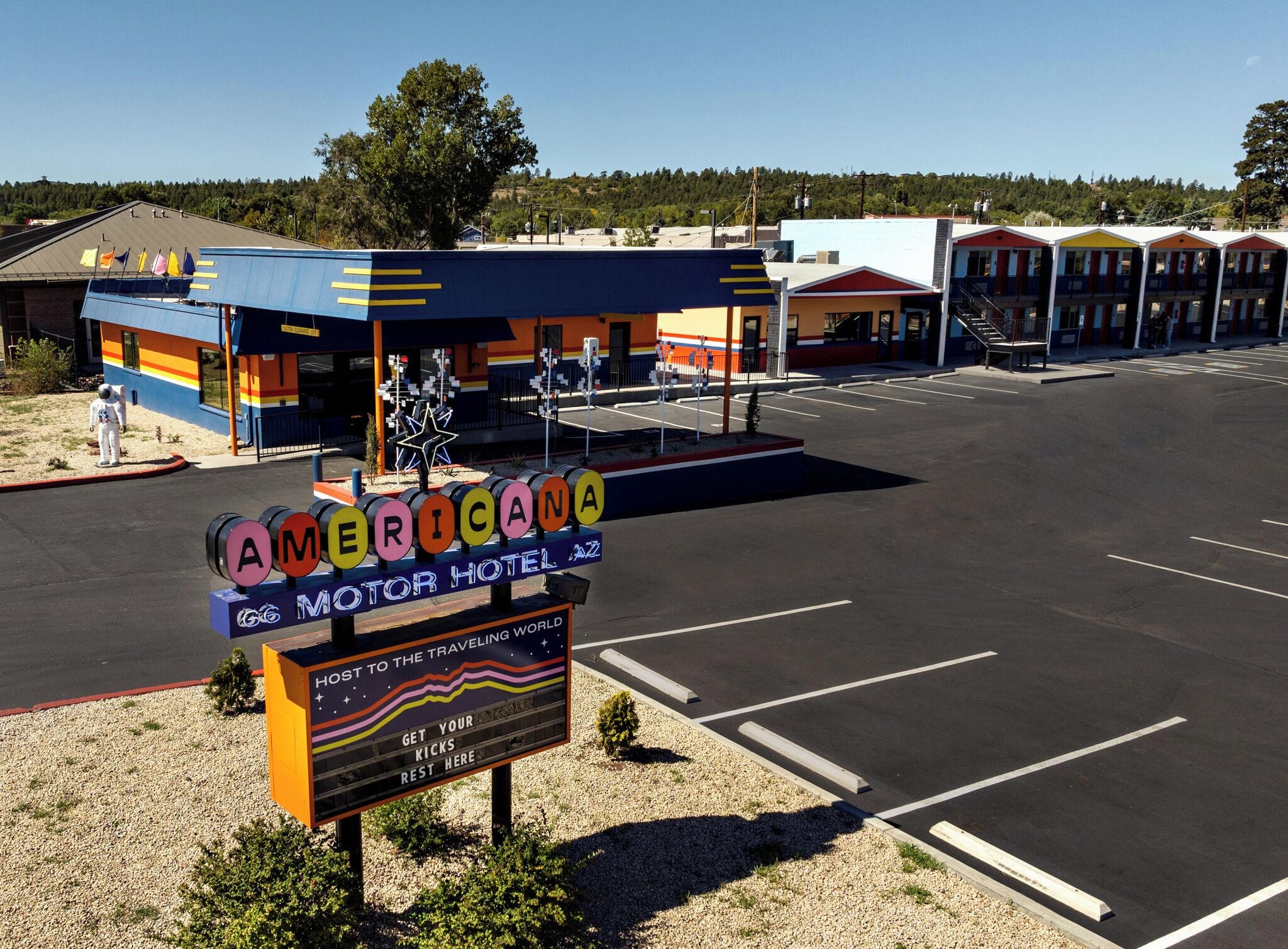 Un motel avec une enseigne aux couleurs vives, un parking et un bâtiment en arrière-plan.