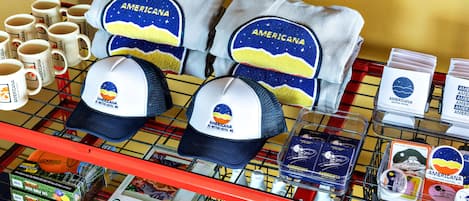 Estante com artigos de lembrança com tema americano, incluindo chapéus, canecas e um conjunto de discos de golfe.