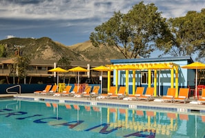 Een buitenzwembad, parasols bij het zwembad en ligstoelen