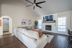 Relax in this cozy living space with a fireplace, comfortable sofa, and large windows.