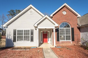 Stunning two-story home with a unique blend of white siding and red brickwork, featuring a charming arched window and inviting porch.