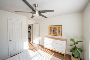 Stylish hallway with a dresser, artwork, and potted plant, leading to a door.