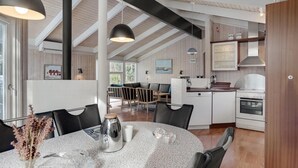 Una cocina moderna con armarios blancos, una estufa y un comedor con una mesa redonda y sillas.
