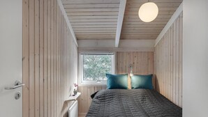 Un dormitorio con paredes de madera, una cama, un ventanal y un radiador.