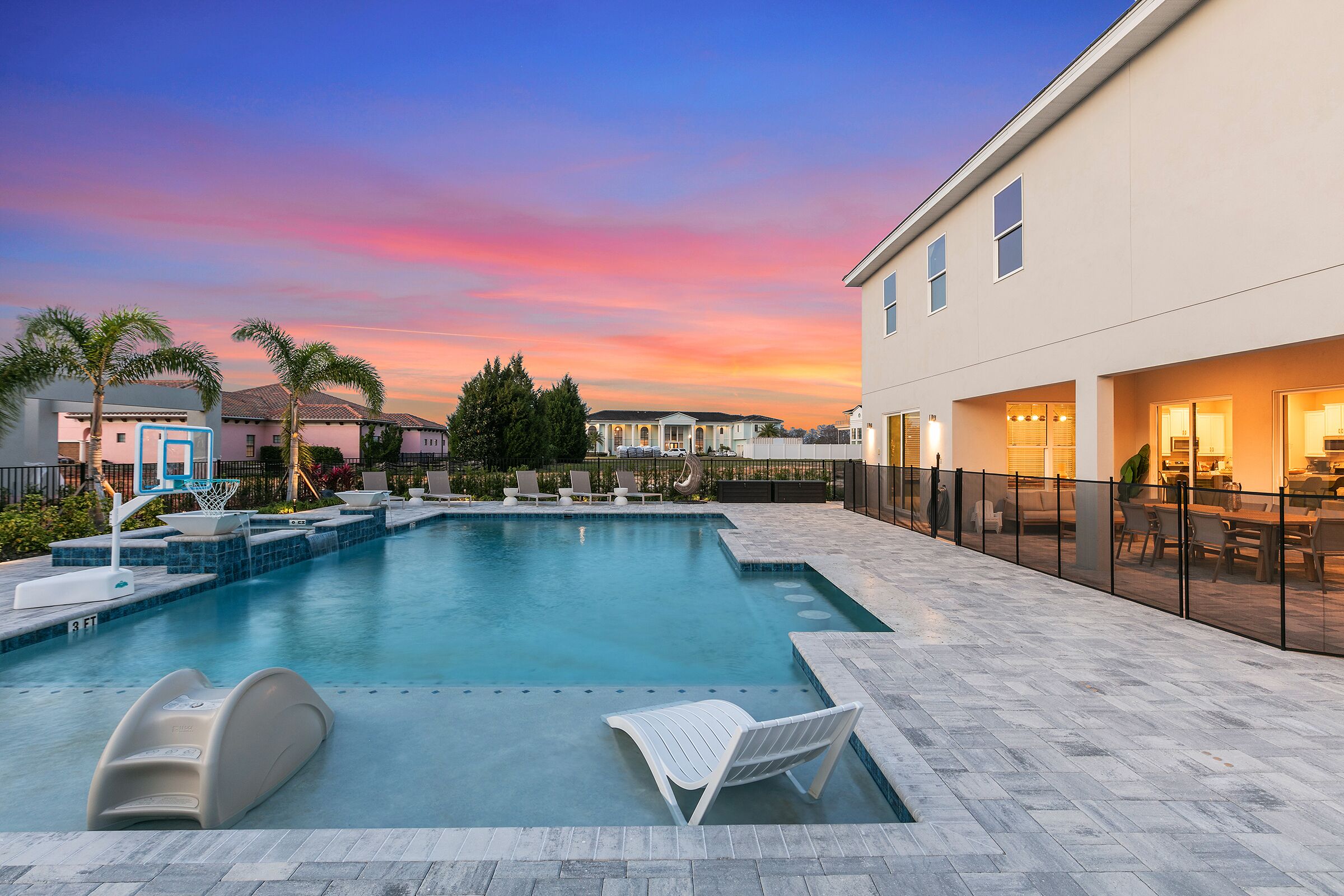 A swimming pool with lounge chairs, a water slide, and a covered patio area.