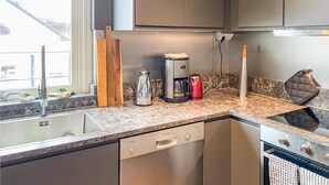 Eine moderne Küche mit eingebautem Geschirrspüler, Kaffeemaschine und Wasserkocher auf der Arbeitsfläche.