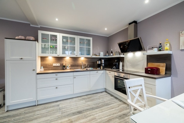 Una cocina moderna con armarios blancos, encimera de madera y horno empotrado.