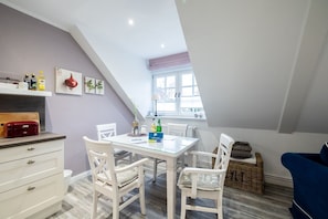 Cocina compacta con una mesa de comedor, sillas blancas y una ventana con vistas.