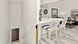 A modern living room with a staircase, a dining area with white chairs, and a sofa. - Beachfront home with Sweeping Ocean Views, AC, Walk to the Pier, Restaurants, Shops, Activities (Newport Beach)