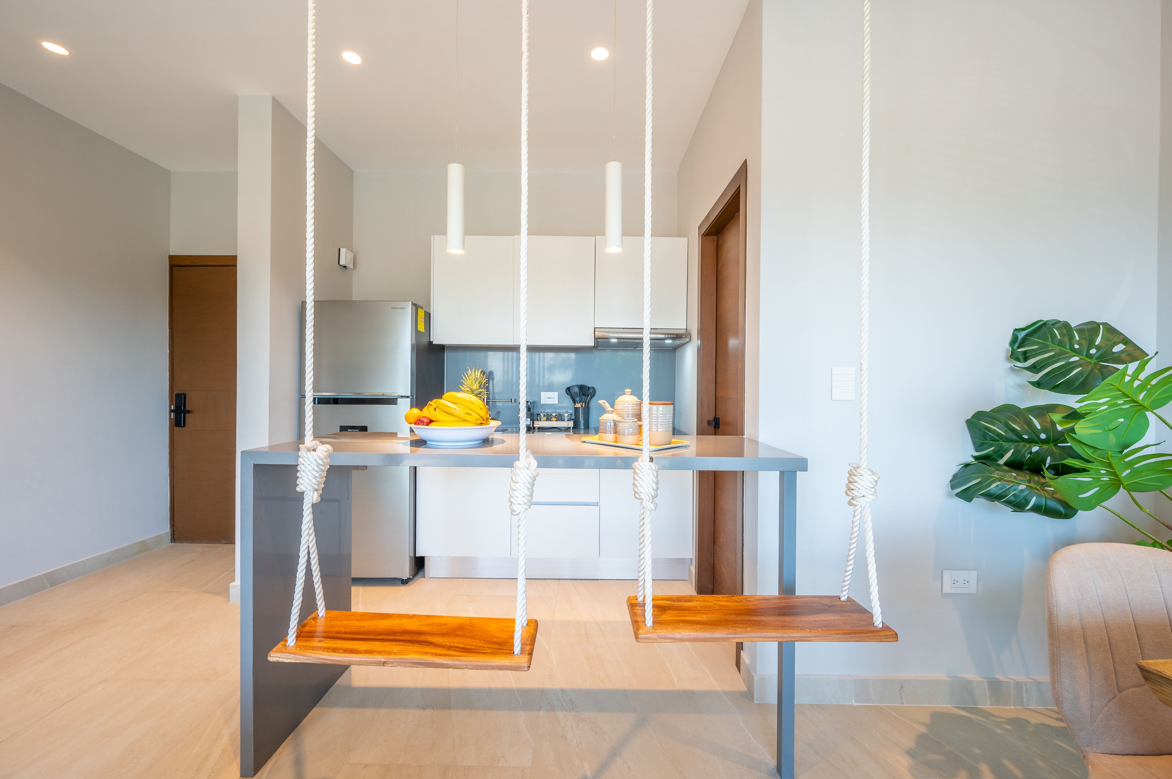 Una cocina moderna con armarios blancos, encimera de madera y un columpio colgante.