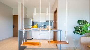 Una cocina moderna con armarios blancos, encimera de madera y un columpio colgante.