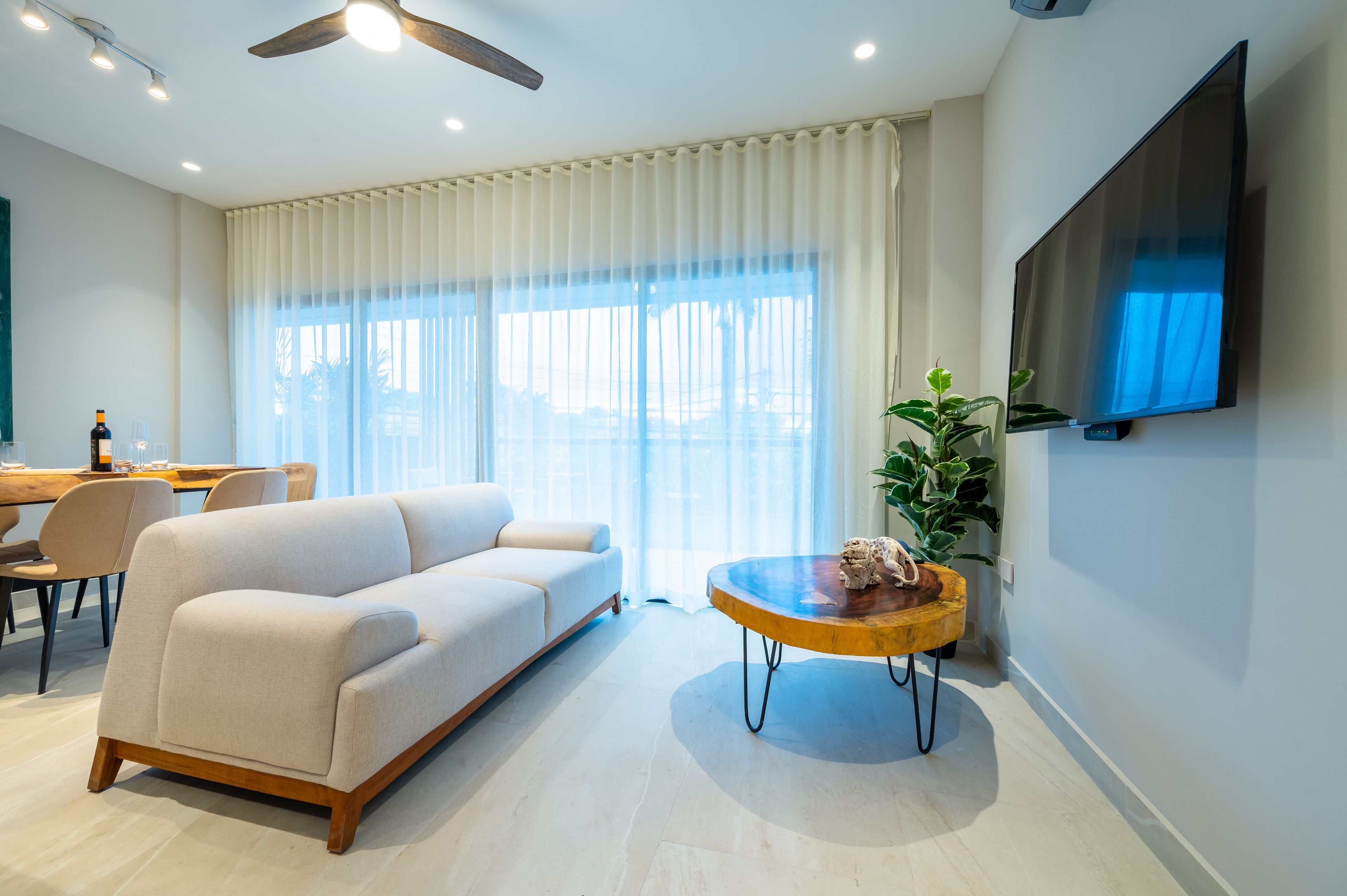 Uma sala de estar moderna com um sofá, uma mesa de centro e uma televisão fixada na parede.