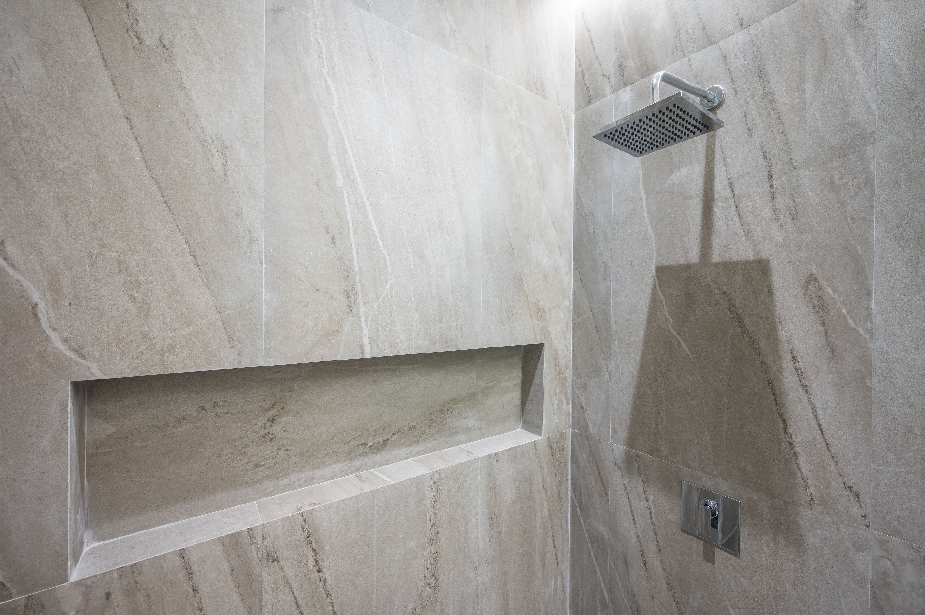 A modern bathroom with a built-in shower, a rectangular sink, and a wall-mounted light fixture.