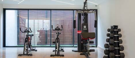 Ett modernt gym med motionscyklar, en styrketräningsmaskin och ett ställ med hantlar.