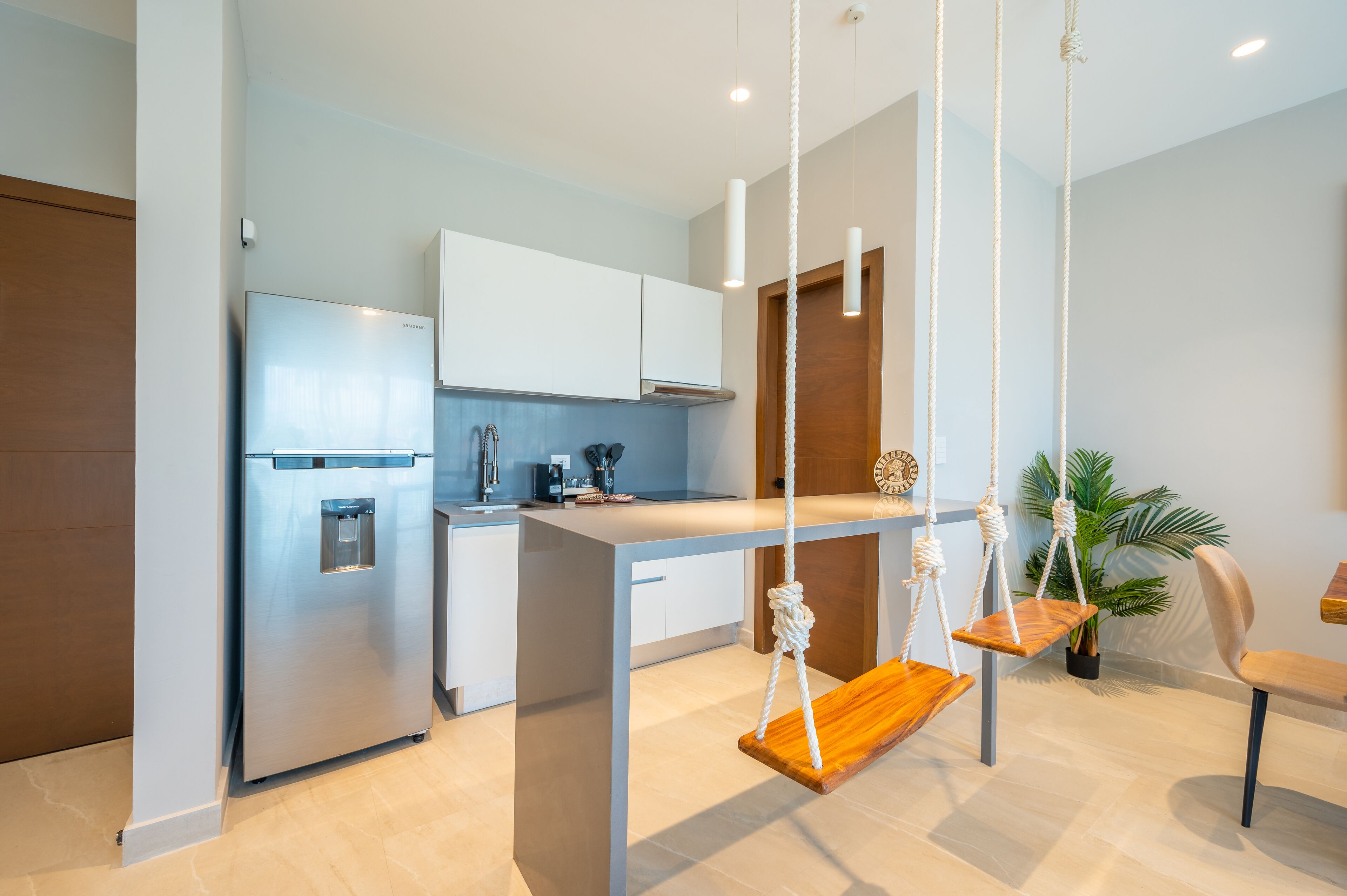 Una cocina moderna con armarios blancos, un refrigerador de acero inoxidable y una isla de madera con un columpio colgante.